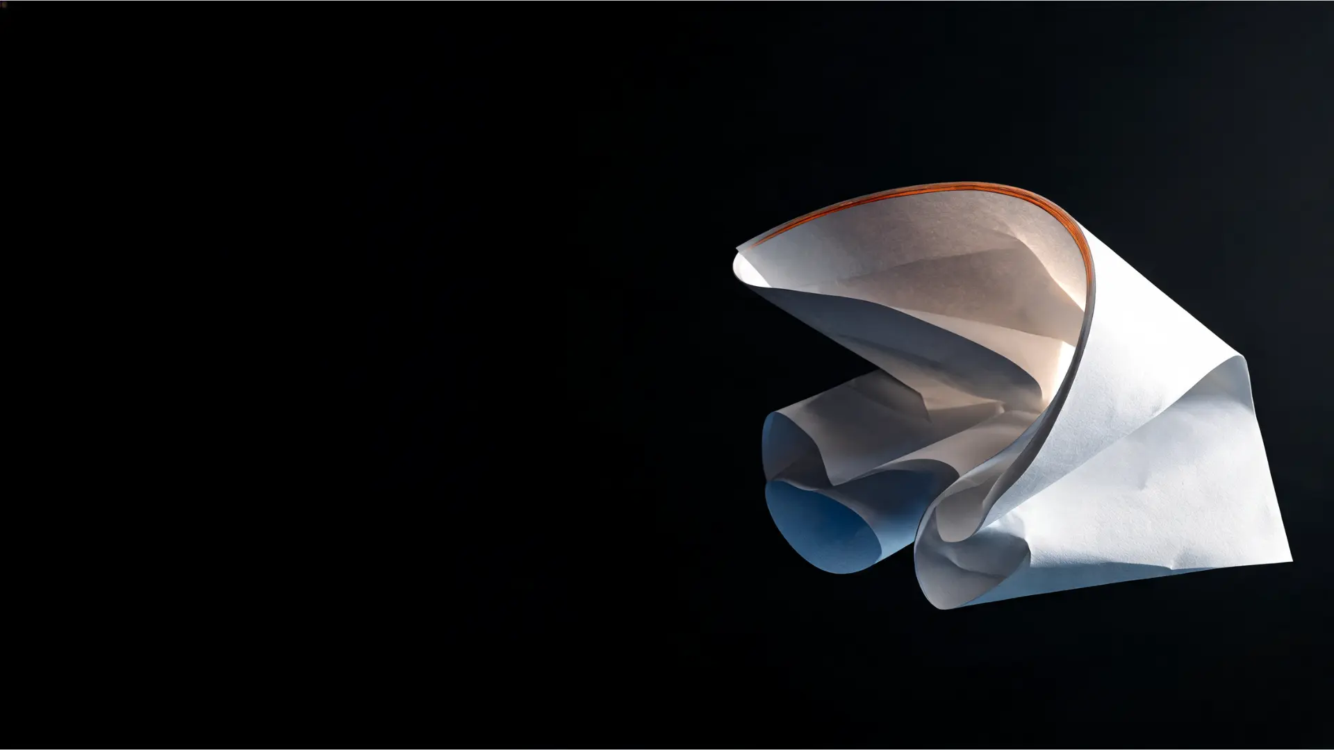 Foglio di carta bianca curvato in una forma scultorea, illuminato da luce radente su fondo nero